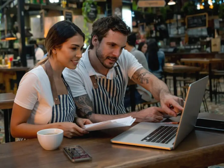 Two restaurant workers looking at laptop at table after work