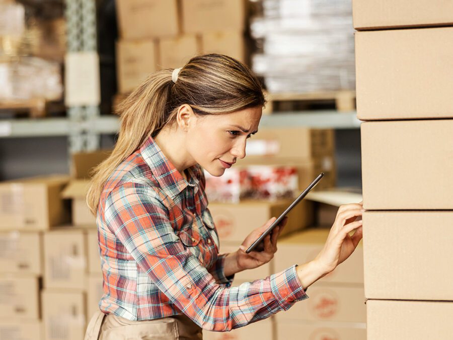 Warehouse worker in plaid shirt using a tablet to check FSMA 204 Compliance