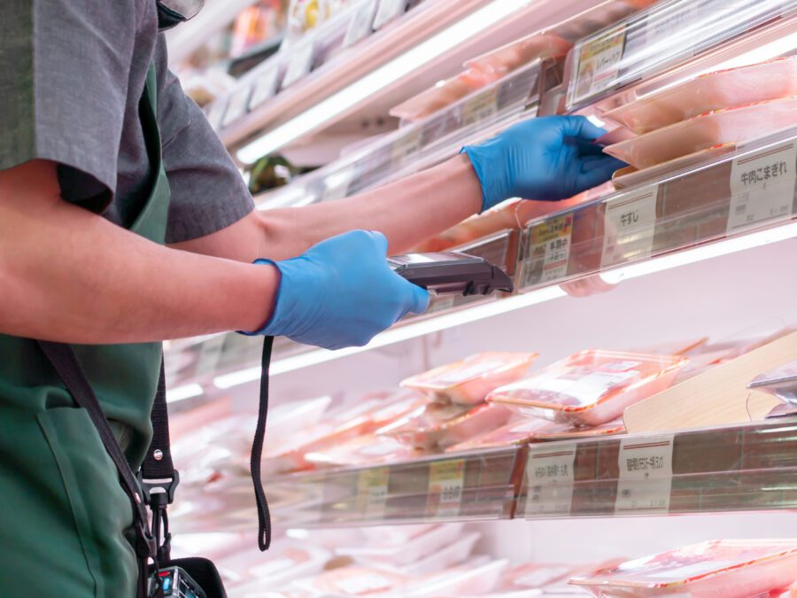 Worker scanning food packages with bar code scanner in cold storage.