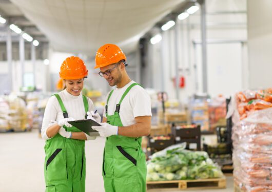 Young people in protective uniform working at organic food distribution.
