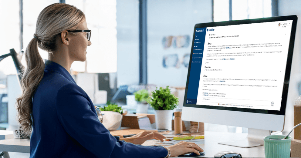 Woman in blazer typing at desktop computer showing Trustwell's AskReg