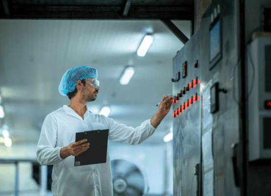 Factory worker monitoring control panel in sterile environment, highlighting FSMA 204 compliance delay impact on food safety protocols.