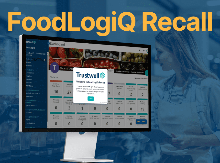 Monitor showing Trustwell’s FoodLogiQ Recall dashboard for managing product recalls, with female worker holding tablet in background.