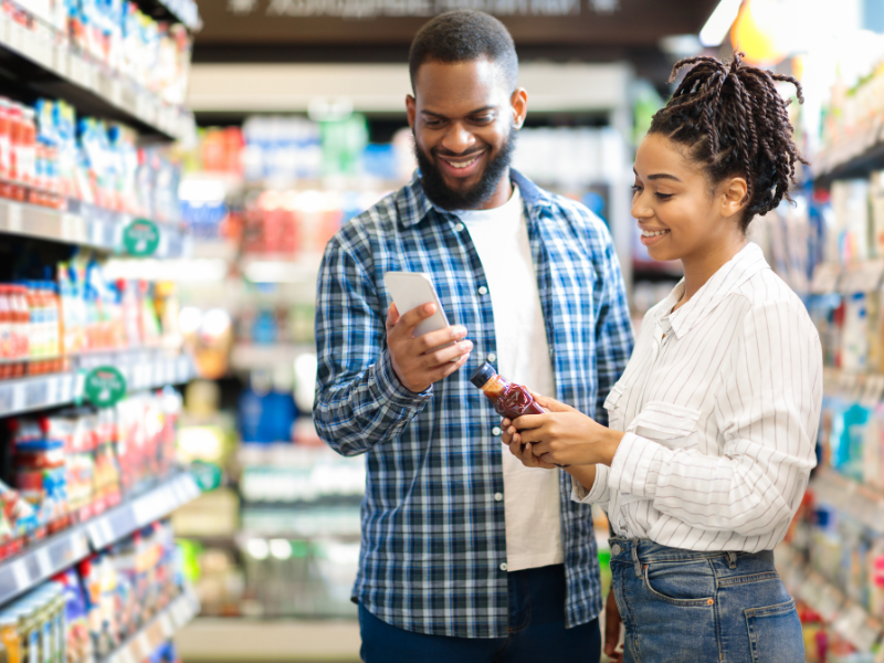 Young black couple looking at a food label while shopping for groceries